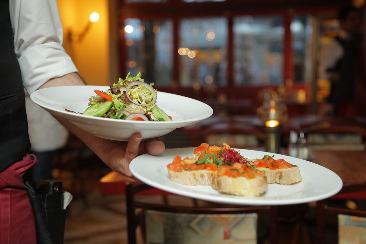 Server presenting plated dishes in a restaurant